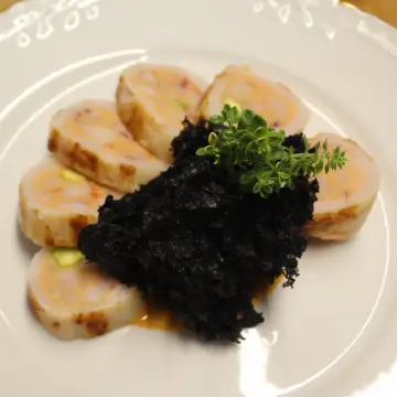 primer plano del Calamar relleno de pescado y gambas cortado, esponja de tinta y salsa Oñana